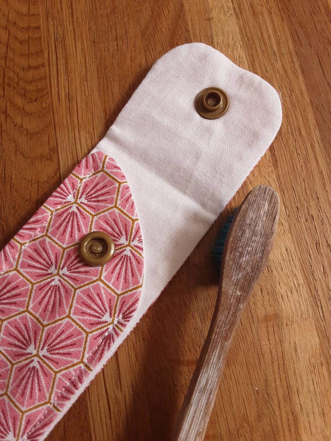 zoom sur l'ouverture de l'étui brosse à dent rose, rabat ouvert, doublure écru et fermeture avec une pression dorée.