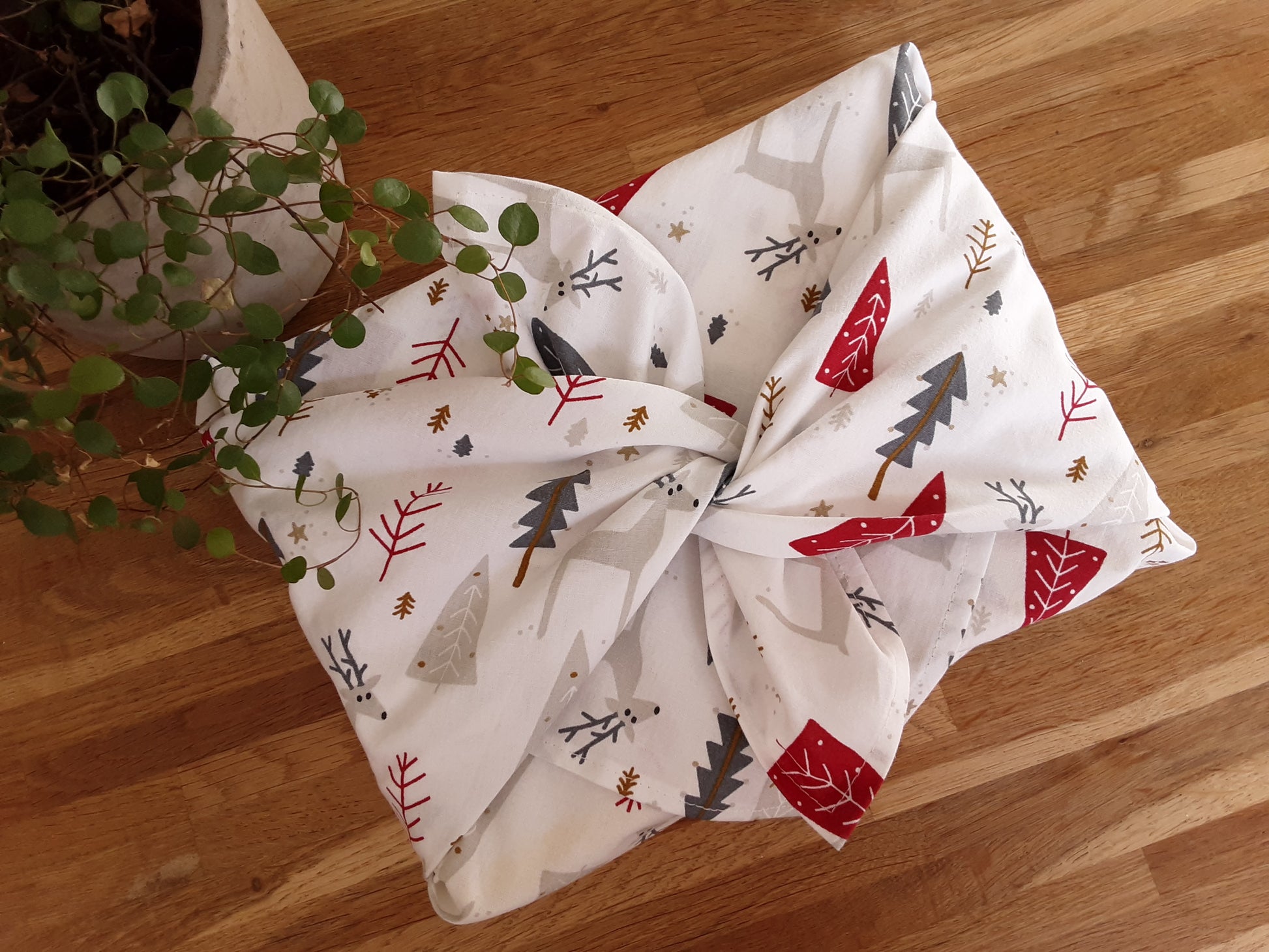 furoshiki, tissu pour emballage cadeau réutilisable et lavable. motifs de noel avec sapin et rennes dans les tons blanc, rouge et gris. accessoire zéro déchet. emballage simple et rapide.