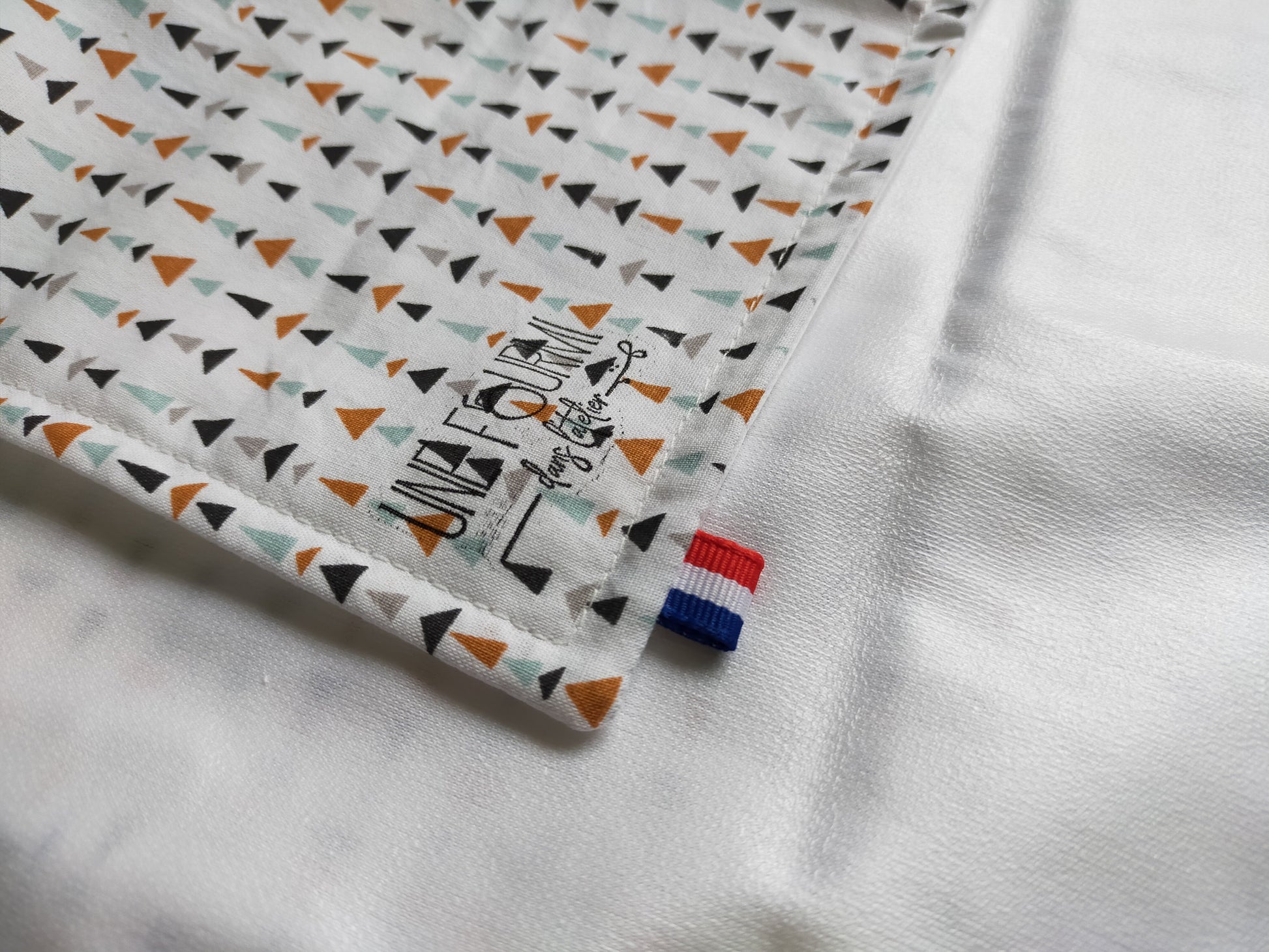 zoom sur la couture de le wrap à sandwich avec le nom de la marque de le ruban tricolore. Doublure en PUL, matériau imperméable.