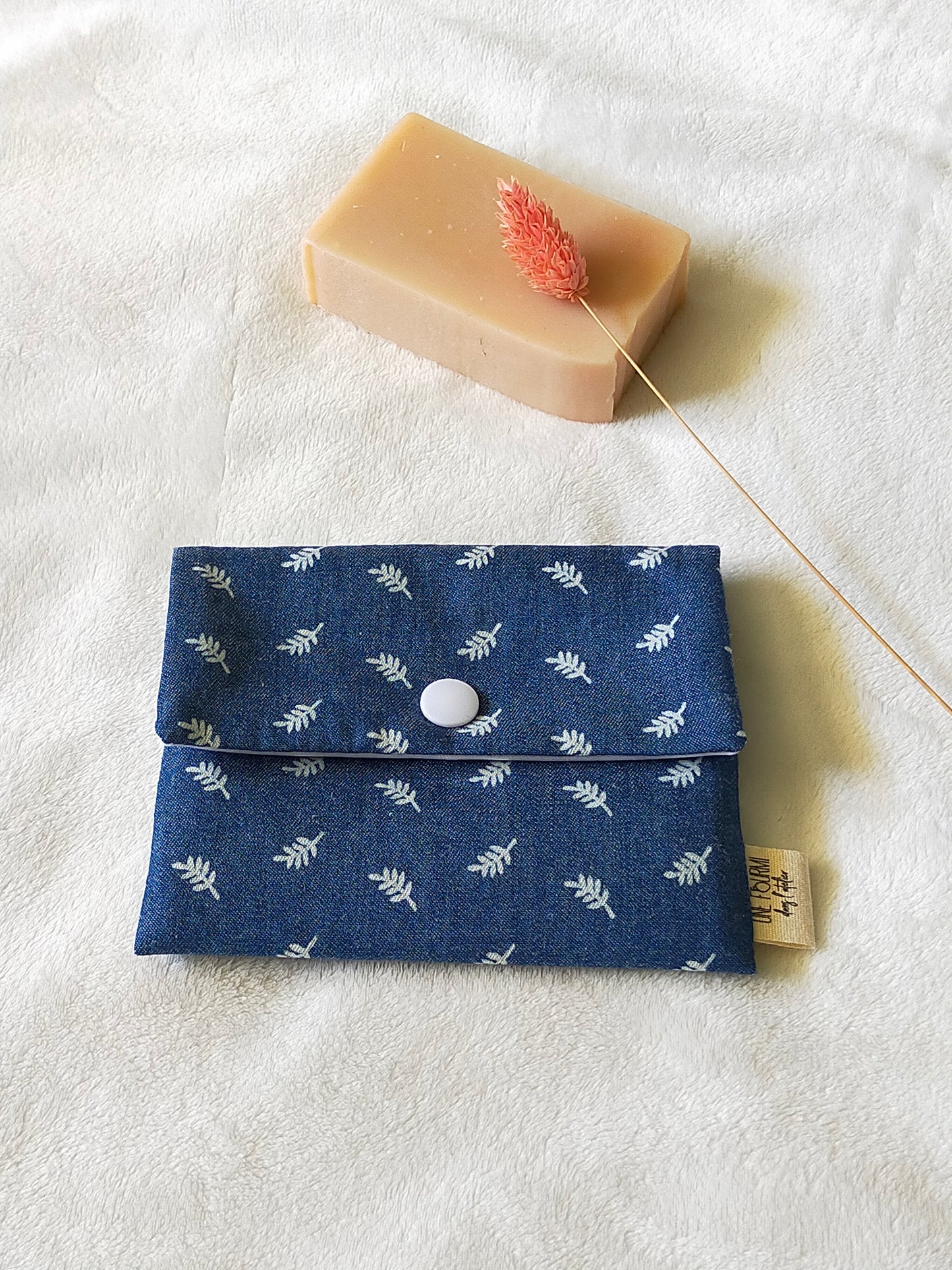 Vue de dessus de la pochette à savon couleur blue jean avec les motifs de fougères. Fermeture avec une pression blanche.