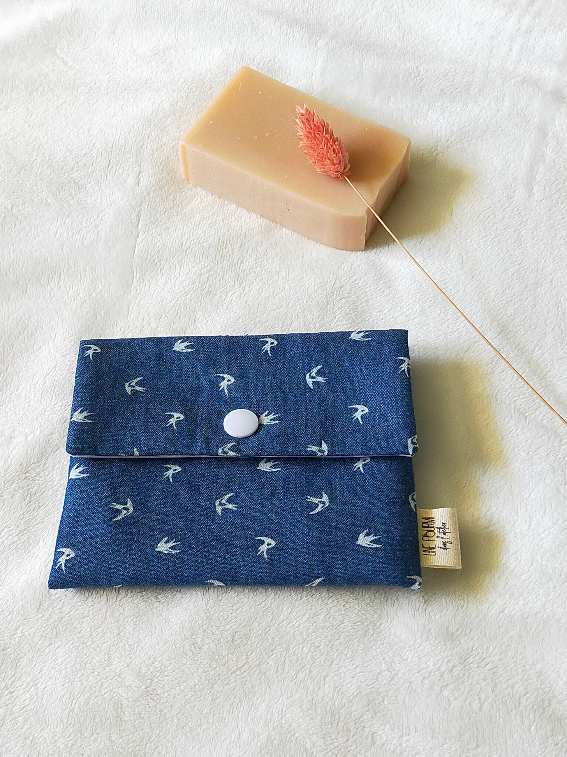 Vue de dessus de la pochette à savon couleur blue jean avec les motifs d'oiseaux. Fermeture avec une pression blanche.