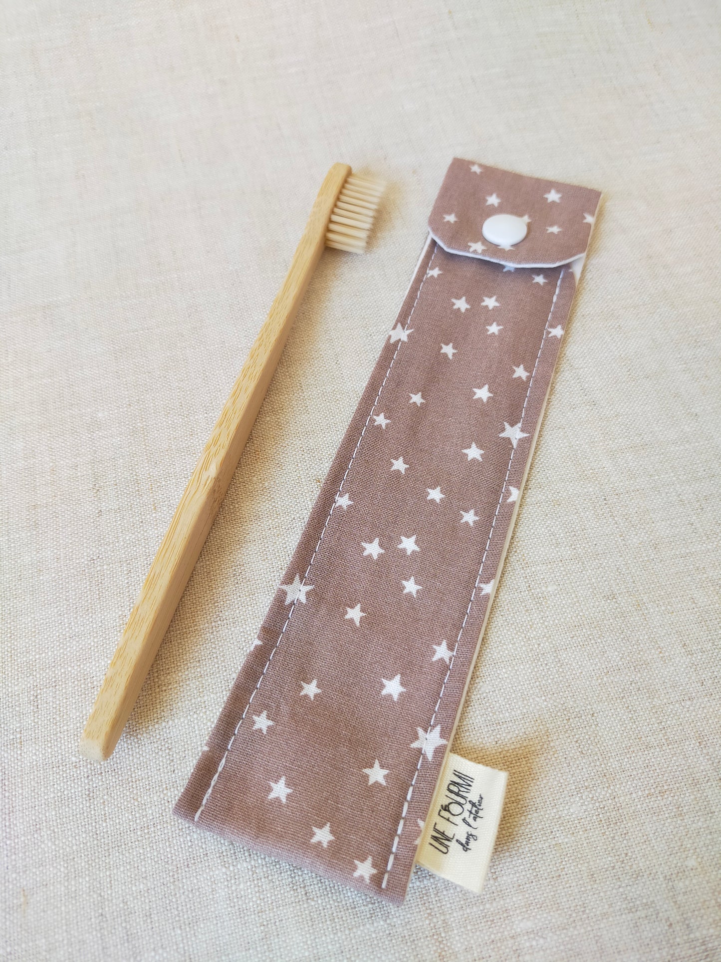 étui pour brosse à dent de couleur taupe, beige, avec des étoiles blanches en motif. accessoire de voyage pratique et utile. accessoire de trousse de toilette.