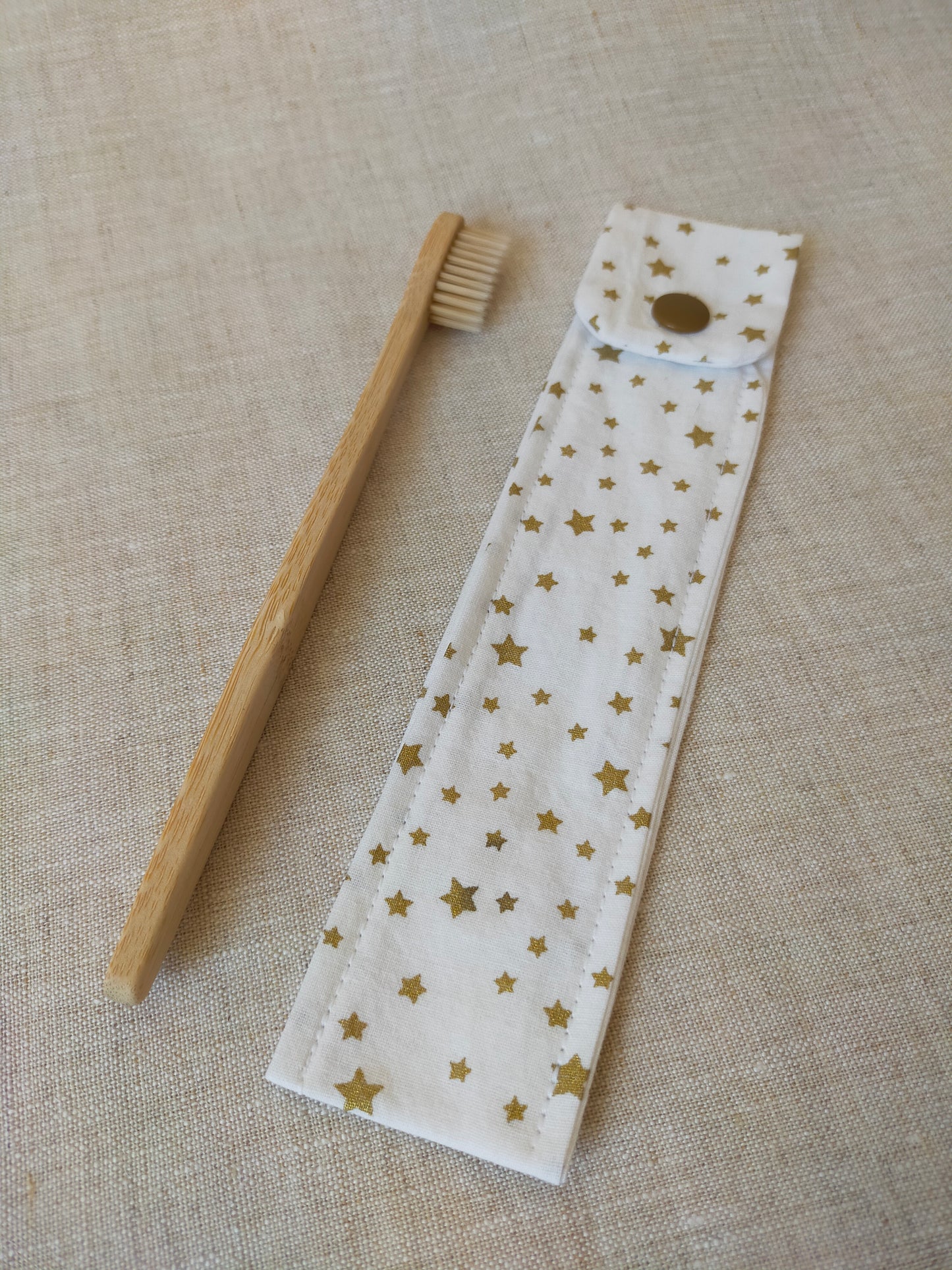 étui pour brosse à dent de couleur blanc, avec des étoiles dorées en motif. accessoire de voyage pratique et utile. accessoire de trousse de toilette.