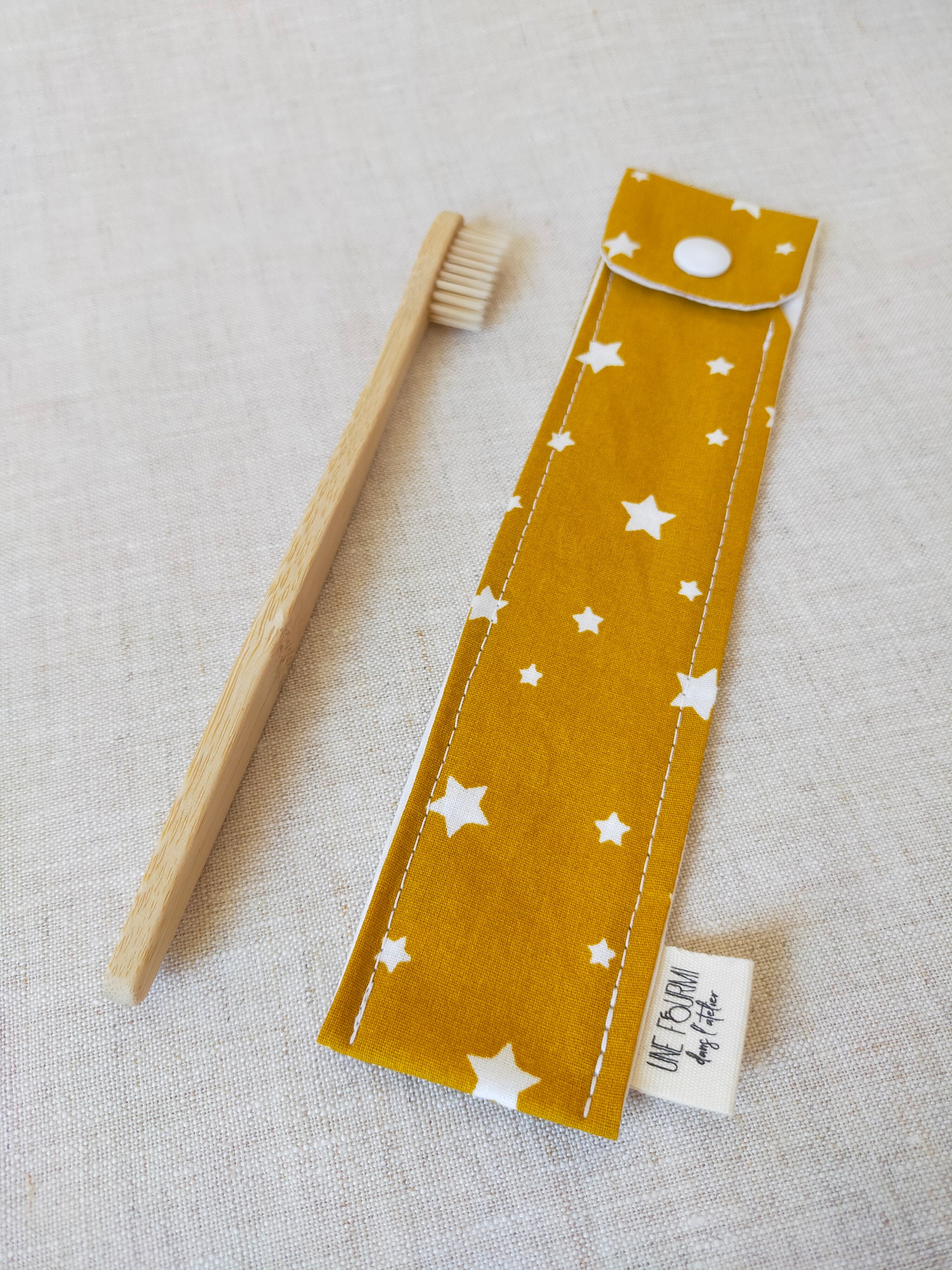 étui pour brosse à dent de couleur jaune moutarde avec des étoiles blanches en motif. accessoire de voyage pratique et utile. accessoire de trousse de toilette.