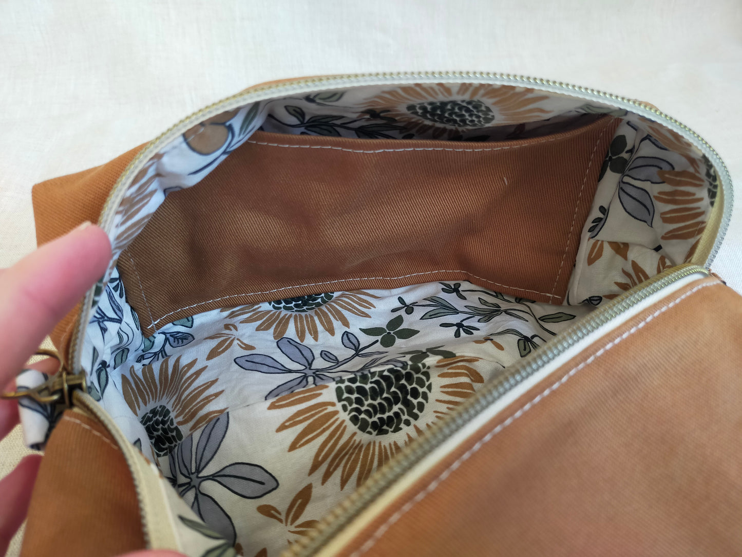 zoom sur la poche plaquée intérieur de la trousse de toilette. Elle est en gabardine de même couleur que l'extérieur de la trousse. Doublure avec motifs tournesols.