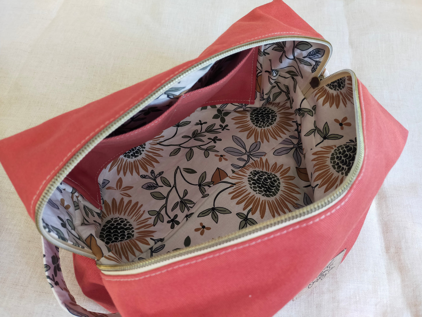 Vue intérieure de la grande trousse de toilette terracotta. 2 poches plaquées et doublure avec des tournesols.