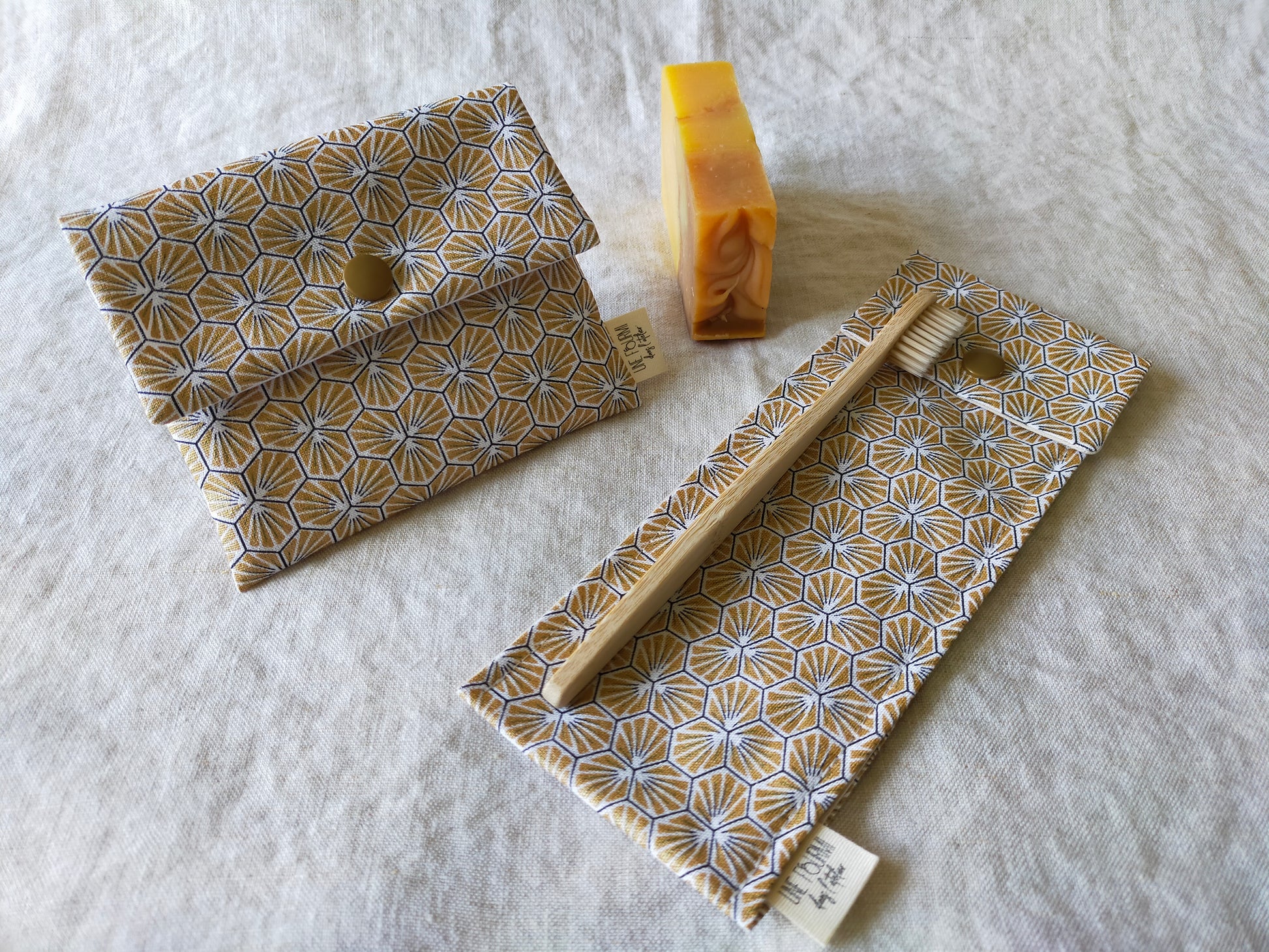 Ensemble 2 pièce d'accessoire de toilette pour le voyage. Pochette à savon imperméable et étui pour brosse à dent et dentifrice. Tissu doré motifs géométriques. Voyager léger et pratique. consommation écoresponsable et zéro déchet.