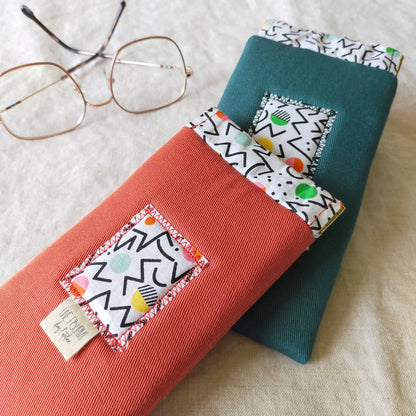 Etui à lunettes rembourré en coton avec fermoir à cliquet. couleur orange ou bleu canard et doublure aux motifs graphiques style Keith Haring