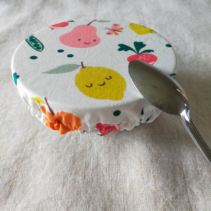 mini charlotte couvre bol pour ramequin et petit récipient de cuisine. accessoire zéro déchet pratique et utile. tissu fond blanc avec dessins fruits et légumes