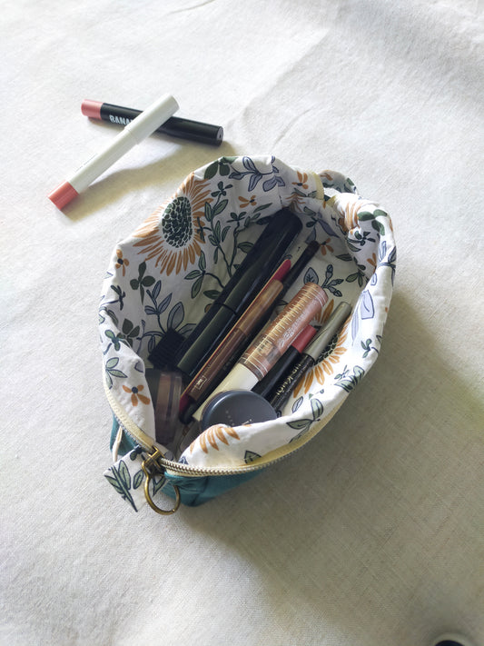 Trousse de toilette panière. Vue de dessus, trousse ouverte maquillage rangé à l'intérieur. Doublure motifs Tournesols