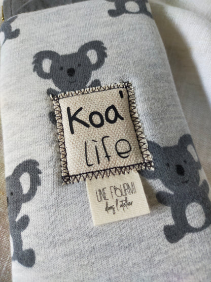 zoom sur le patch cousu sur l'avant de l'étui à lunette. inscription Koa'life avec insertion de l'étiquette de la marque Une fourmi dans l'atelier.