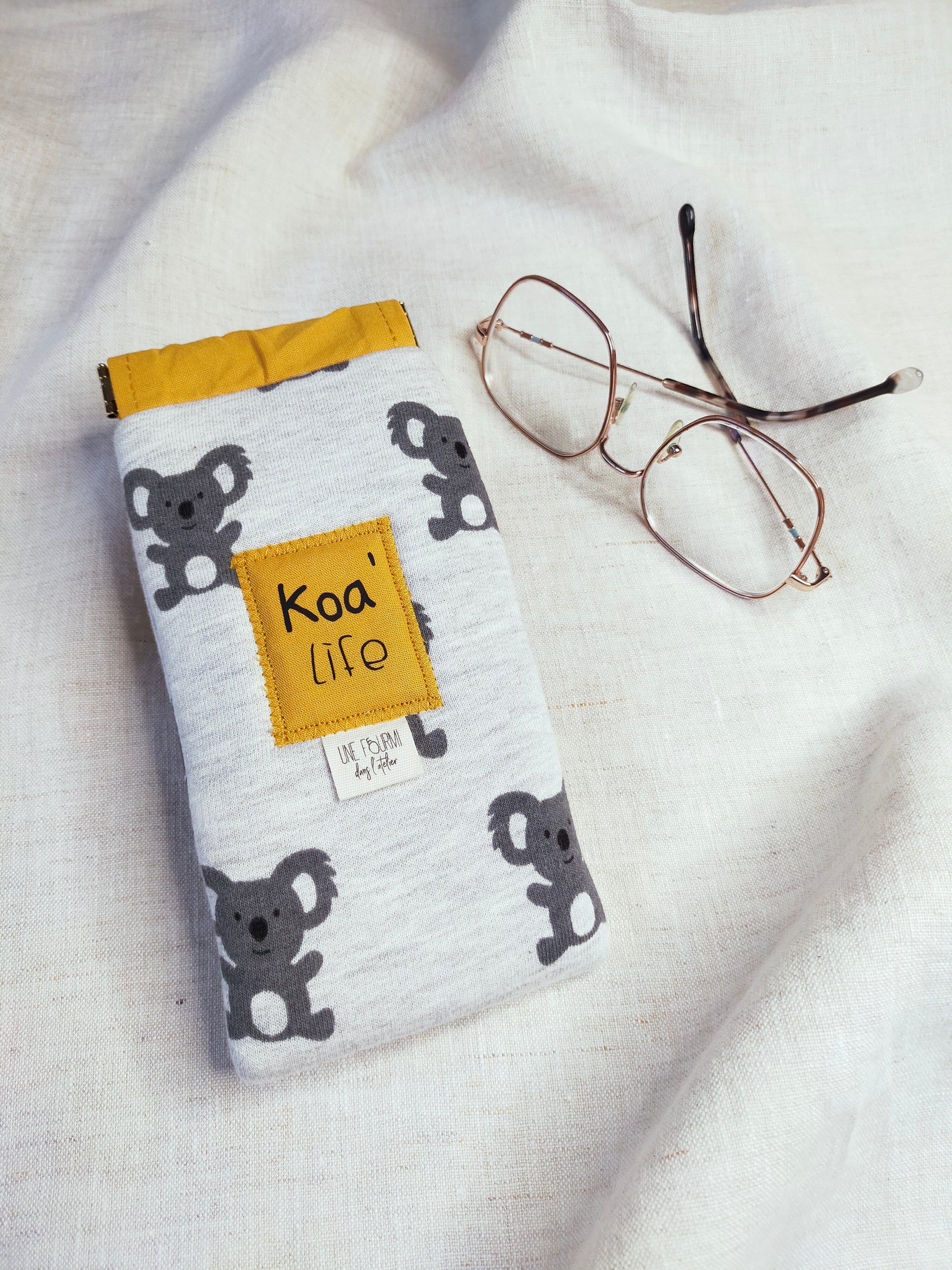 vue dessus, étui à lunette rembourré avec les motifs de Koala et la doublure Jaune. Patch sur l'avant avec inscription Koa'Life