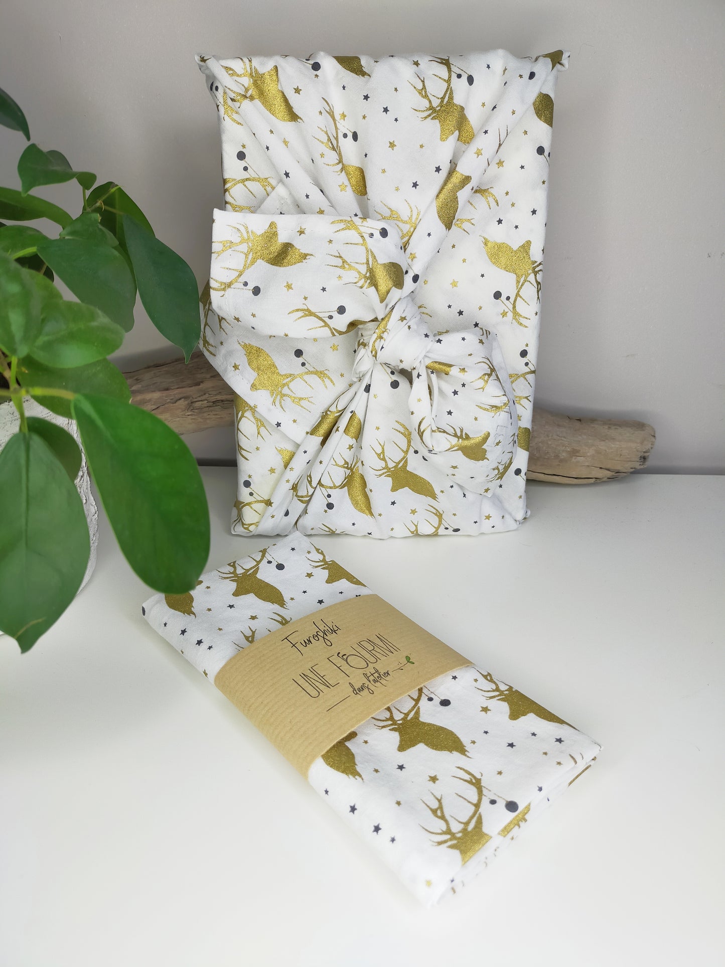 furoshiki avec tissu blanc et motifs de rennes dorés. emballage cadeau écologique et réutilisable