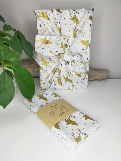 furoshiki avec tissu blanc et motifs de rennes dorés. emballage cadeau écologique et réutilisable